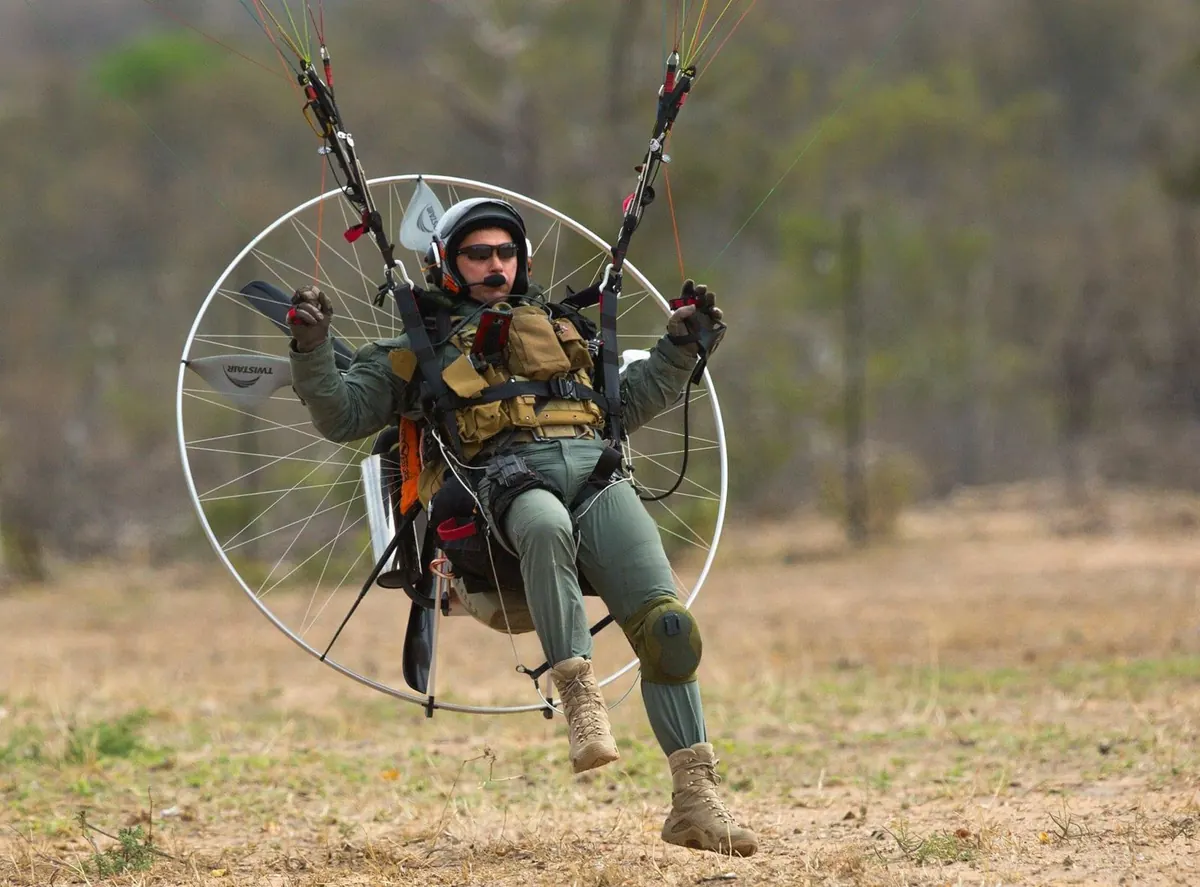 Eugene Cussons landing under a paramotor in a flight suit and helmet with headset
