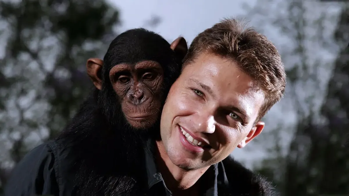 Eugene Cussons smiling with a young chimpanzee on his shoulder