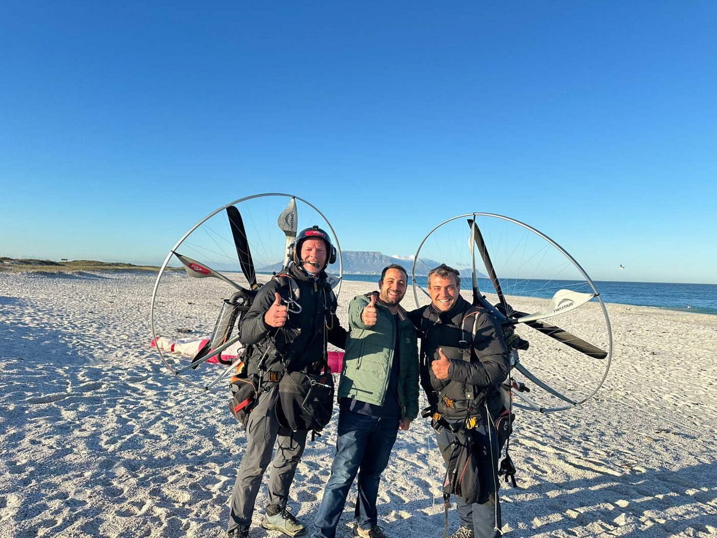 Two pilots with their paramotors on Blouberg beach with Table Mountain behind