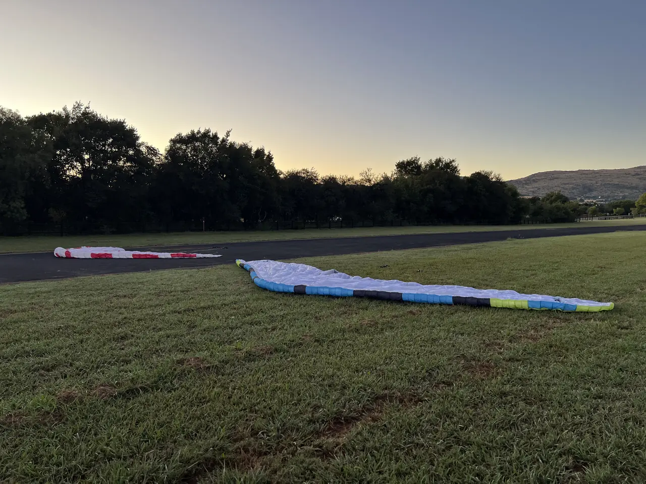 A paramotor wing laid out on grass at dawn on an airfield on Day 1