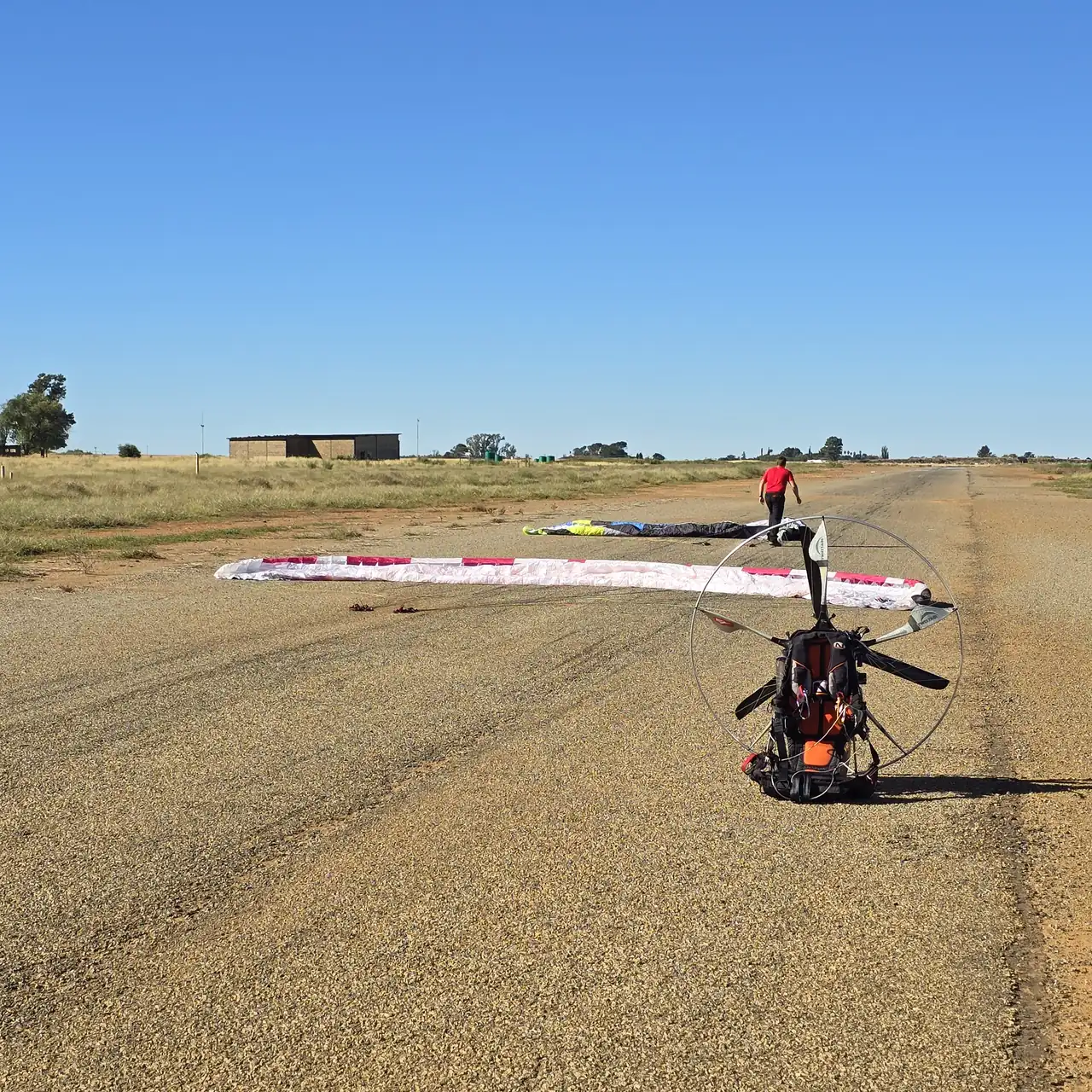 A paramotor and a wing spread out on a gravel airstrip on Day 1