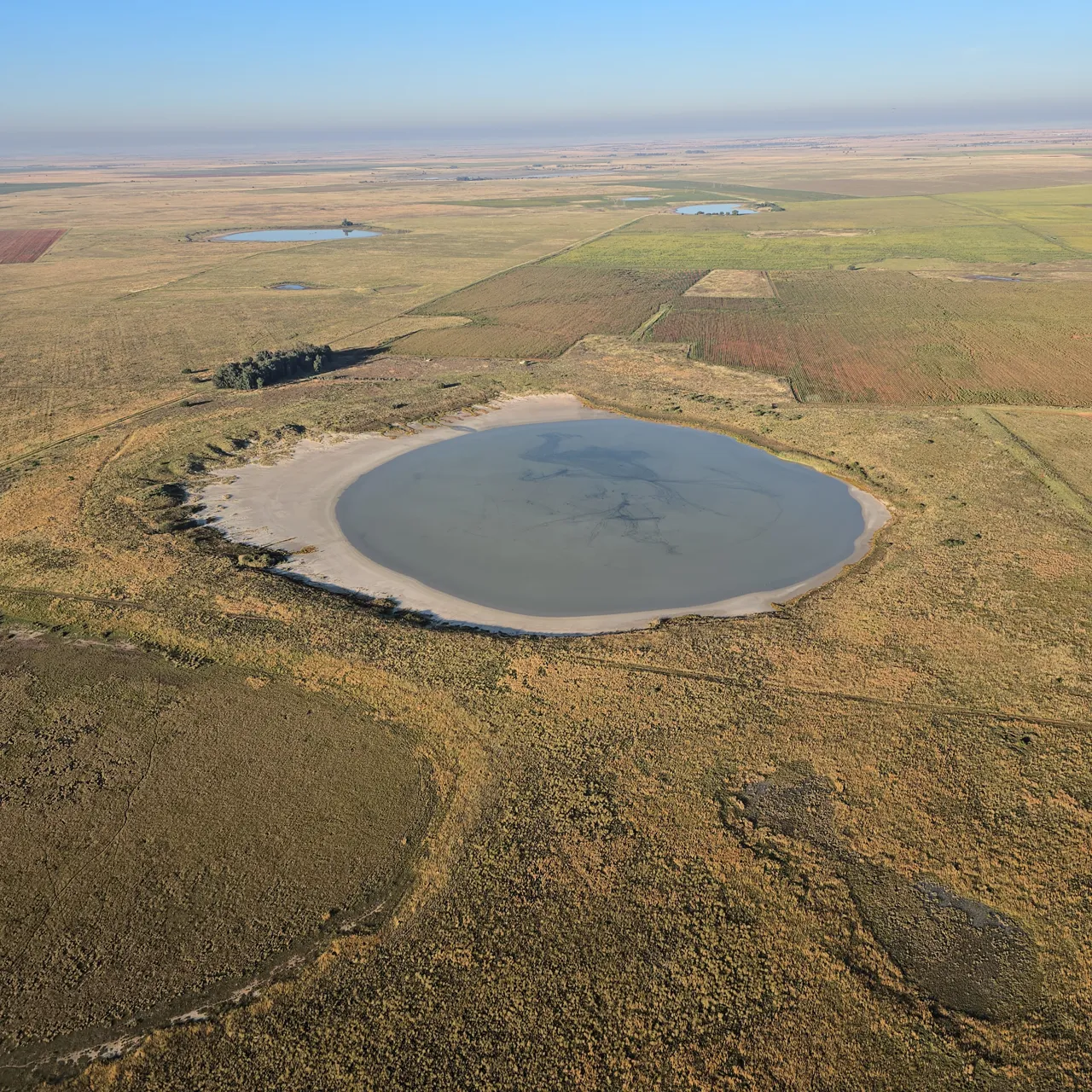 A round pan of water in dry farmland seen from the paramotor on Day 2