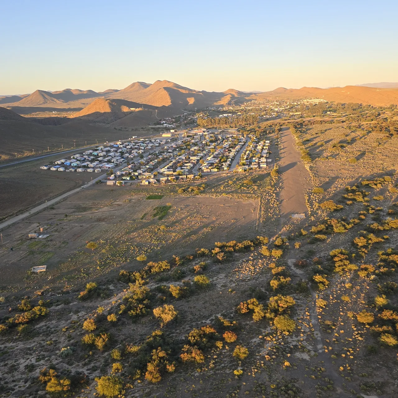 A town below the mountains in golden evening light, seen from the air on Day 3