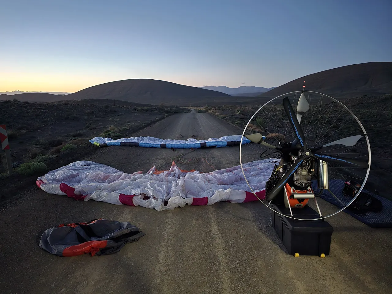 Wings laid out on a road at first light on Sunday, with hills in the background