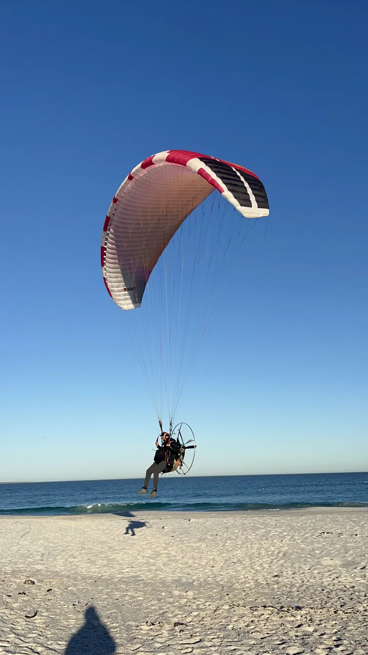 A pilot under a wing coming in to land on the beach on Day 5
