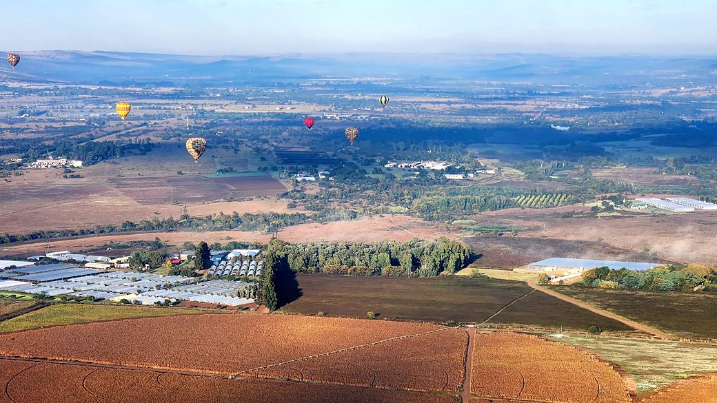 Aerial view of hot air balloons over farmland and a town
